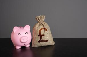 Happy piggy bank and british pound sterling money bag. Loans and credits, mortgage. Economics and currency exchange, stock market. Banks and finance. Investments. Funding and grants. Deposits photo