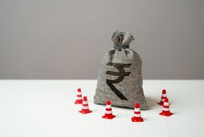 Indian rupee money bag blocked by road cones. Freezing of accounts and sanctions on capital. Suspicious funds with unknown sources. National money reserve. photo