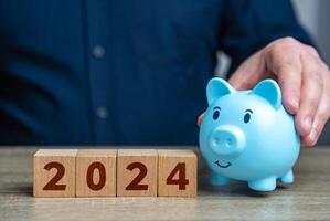 How to manage finances in 2024. Budget and expense planning. Business and finance. Businessman holding piggy bank. photo