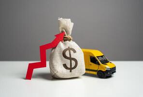 Delivery van and dollar money bag with red arrow up. Increased profits when delivering online orders. Transport industry. Trade and sale of goods. High customer costs for online shopping. photo