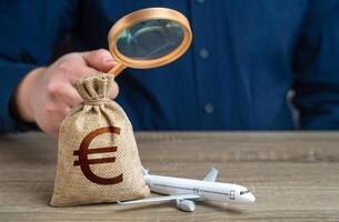 Airplane and euro money bag under investigation. Economic impact of aviation industry. Environmental footprint. Payment of taxes, fees and excise taxes. Measure impact on local economy. photo