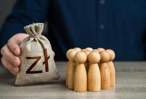 Man offers an polish zloty money bag to a crowd of people figurines. Providing money, paying salaries and grants. Compensation payments. Social assistance to victims of conflict. Financial support. photo