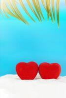 Red hearts on sand with palm of beach behind sea. Valentine's day, wedding, honeymoon, holiday, proposal. Copy space photo