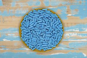 Yellow plate full of blue medicine capsules representing drug overdose photo