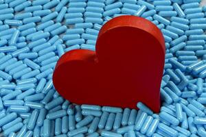 heart shape and medicine capsules representing heart problems and treatment photo