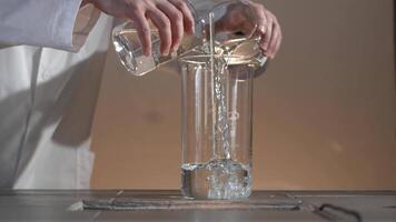 Male researcher carrying out scientific research in a lab. Flasks with liquids in a lab. Liquid in the flask changes color video