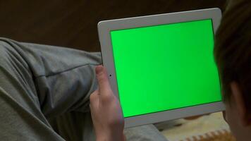 achterzijde visie van wazig Mens Holding een tablet met een blanco bewerkbare groen scherm. Mens Holding tablet met groen scherm - terug visie video