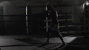 Fighter shadowboxing on training ring. Professional fighter. Male boxer in training sportswear, an exercise in sports hall, fight with a shadow in ring, Strike testing video