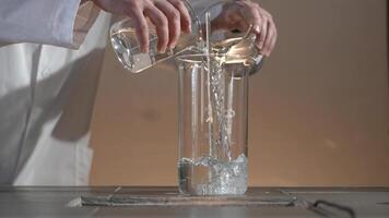 Male researcher carrying out scientific research in a lab. Flasks with liquids in a lab. Liquid in the flask changes color video