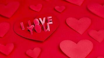 letras, yo amor usted declaración de amor enamorado tarjeta. concepto de amar, San Valentín día, boda. corazones hecho de de colores papel en un rojo antecedentes. animación stopmotion vídeo 4k parte superior ver video