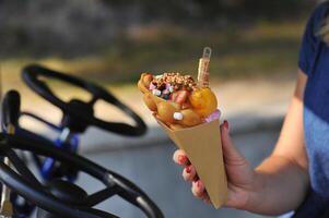 Beautiful delicious ice cream in a cone cone is held in the hands of a girl close up photo