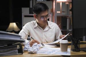 Young businessman working overtime on a desk at night. photo