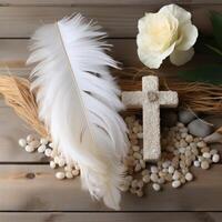 AI generated White stone cross with feather and pebbles on wood background, palm sunday greetings photo