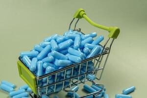 blue medicine capsule in miniature shopping cart photo