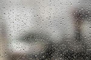 window glass with raindrops showing blurred city in the background photo