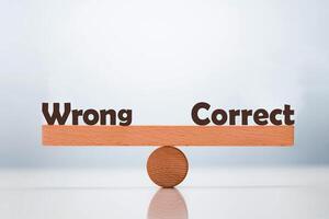 Wrong vs correct word balancing on seesaw choice concept photo