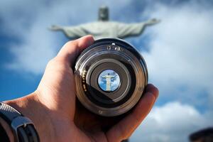 selective focus shot person holding camera lens on  Rio with Corcovado Mountain tourist taking a picture with camera lens on  Rio with Corcovado Mountain photo