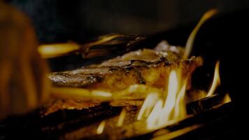 A la parrilla carne filete en inoxidable parrilla deposito con llamas en oscuro antecedentes. comida y cocina concepto. foto