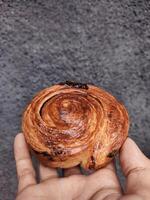 mano participación cromboloni, redondo cuerno, nuevo York rollo, un viral Pastelería combinatorio croissants y bomboloni en hormigón pared antecedentes. foto