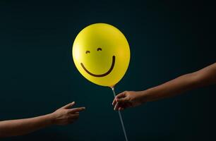 felicidad día, aliento concepto. contento y optimista mente, bien mental salud. persona dando un sonriente globo a otro foto