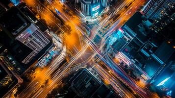 AI generated image is an aerial view of busy city intersection at night. Multiple roads converge at this point, creating an intricate pattern marked by various lanes and crosswalks. Ai Generated photo