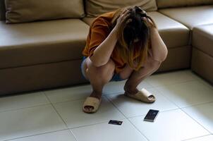 Asian woman holds her head in her hands and sits on the ground in despair after talking with a gang. Scammers and were tricked out of all their money. photo