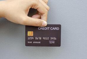 female hand holding a black credit card mockup with security chip embedded on a gray background photo