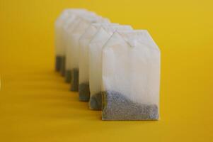 A lot of disposable tea bags on a yellow background. photo