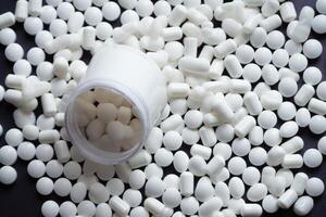 AI generated White medical pills and tablets spilling out of a drug bottle. Macro top down view with copy space. photo