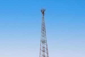 Internet signal tower or mobile phone signal tower isolated on blue sky background texture. Global communication and internet network connection concep photo