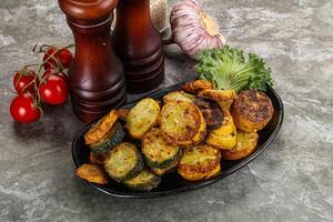 Roasted young zucchini in the plate photo