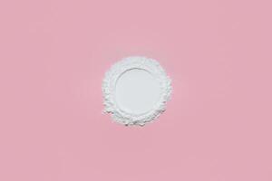 White face powder with empty circle inside on pink background photo