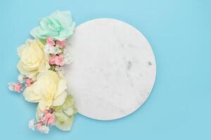 Round marble podium with flowers on blue background photo