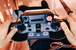 Remote control of a lifting car crane in the hands of a person. A panel with joysticks and buttons for controlling the telescopic bucket of the crane photo