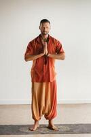 un hombre en un naranja traje lo hace yoga en un aptitud habitación. el concepto de salud foto