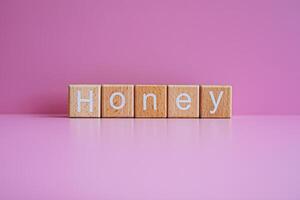 Wooden blocks form the text Honey against a pink background. photo