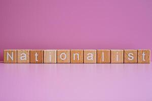 Wooden blocks form the text Nationalist against a pink background. photo