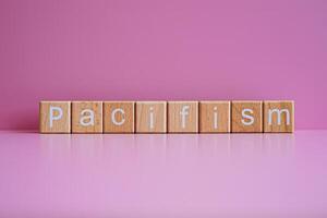 Wooden blocks form the text Pacifism against a pink background. photo