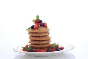 Stacked Pancake with Maple Syrup, Bluberry, Strawberry and Mint Leaf. photo