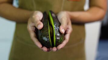 dichtbij omhoog hand- Open avocado fruit. gesneden avocado in de handen van een vrouw. video