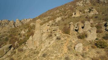 bellissimo autunno paesaggio con insolito rocce e colline nel un' soleggiato giorno. sparo. montagne con bizzarro modulo picchi su appassito, giallo colline sfondo. video