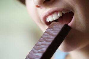 Unrecognizable teenage girl about to eat healthy protein bar at home photo