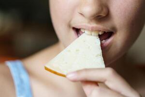 Unrecognizable girl eating delicious cheese slice at home photo