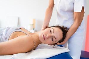 Relaxed woman getting neck treatment in osteopathy clinic photo