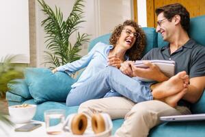 Cheerful couple with pages in living room photo