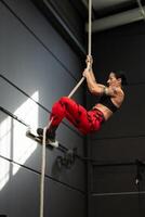 Strong woman climbing a rope in a cross training gym photo