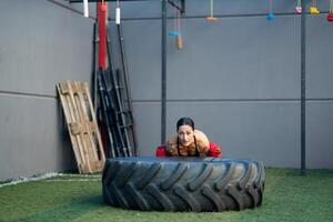 fuerte mujer trabajando fuera con un rueda en un gimnasio foto