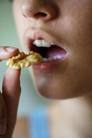 Crop anonymous teenage girl about to eat delicious walnut photo