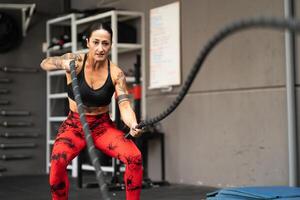 Strong mature woman working out with battle ropes photo
