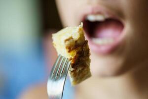 anónimo Adolescente niña acerca de a comer Fresco patata tortilla desde tenedor foto